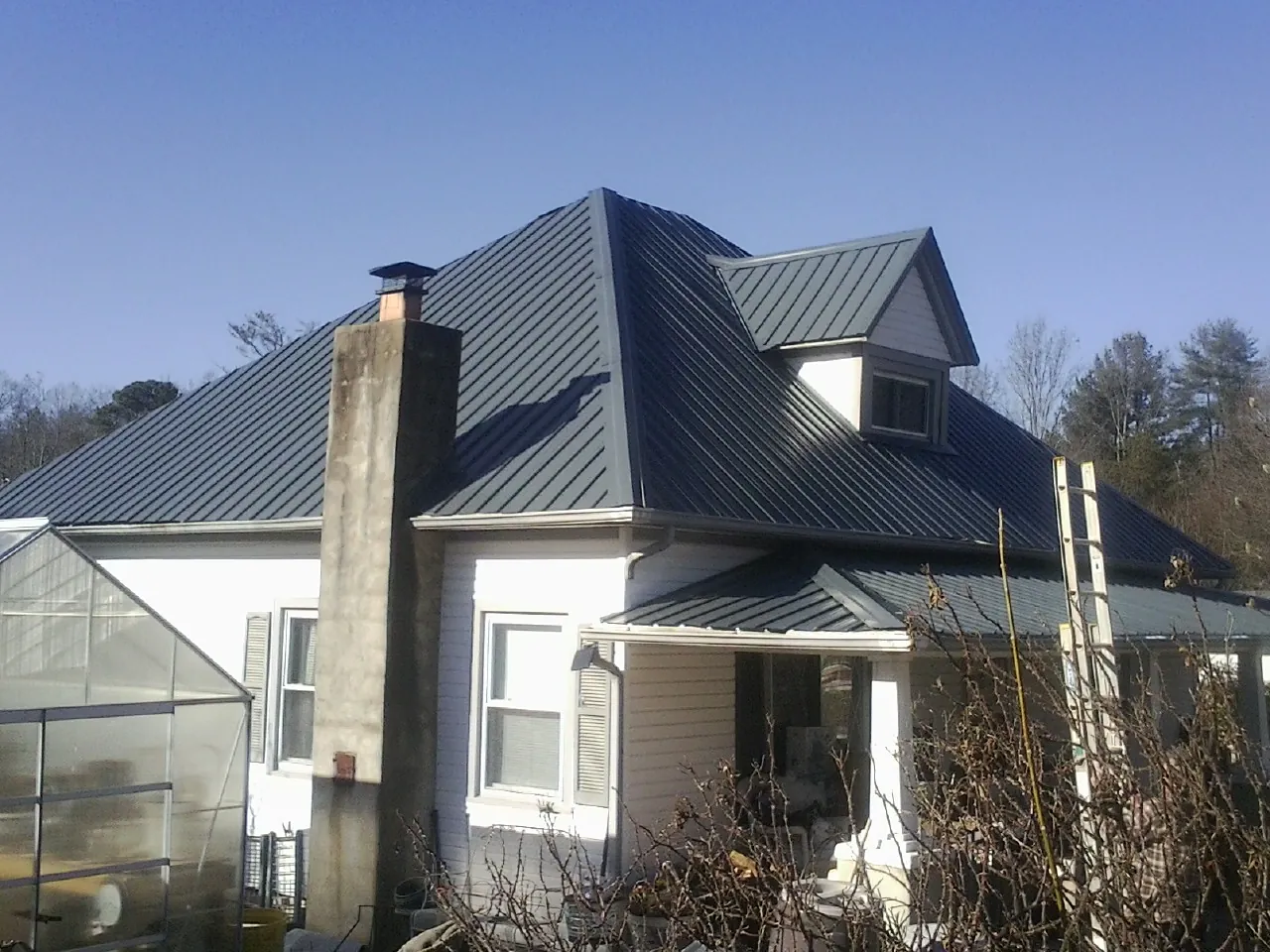 Dark blue standing seam metal roof on a white farmhouse with dormer — Slate & Tile Roof Repair by Roofing Brothers in Pilot Rock
