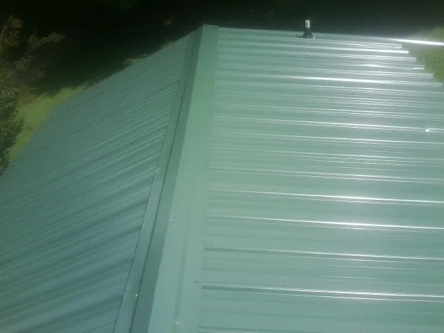 New green metal panels meeting at the ridge of a roof — Flat Roof Repair work by our crew in Pilot Rock