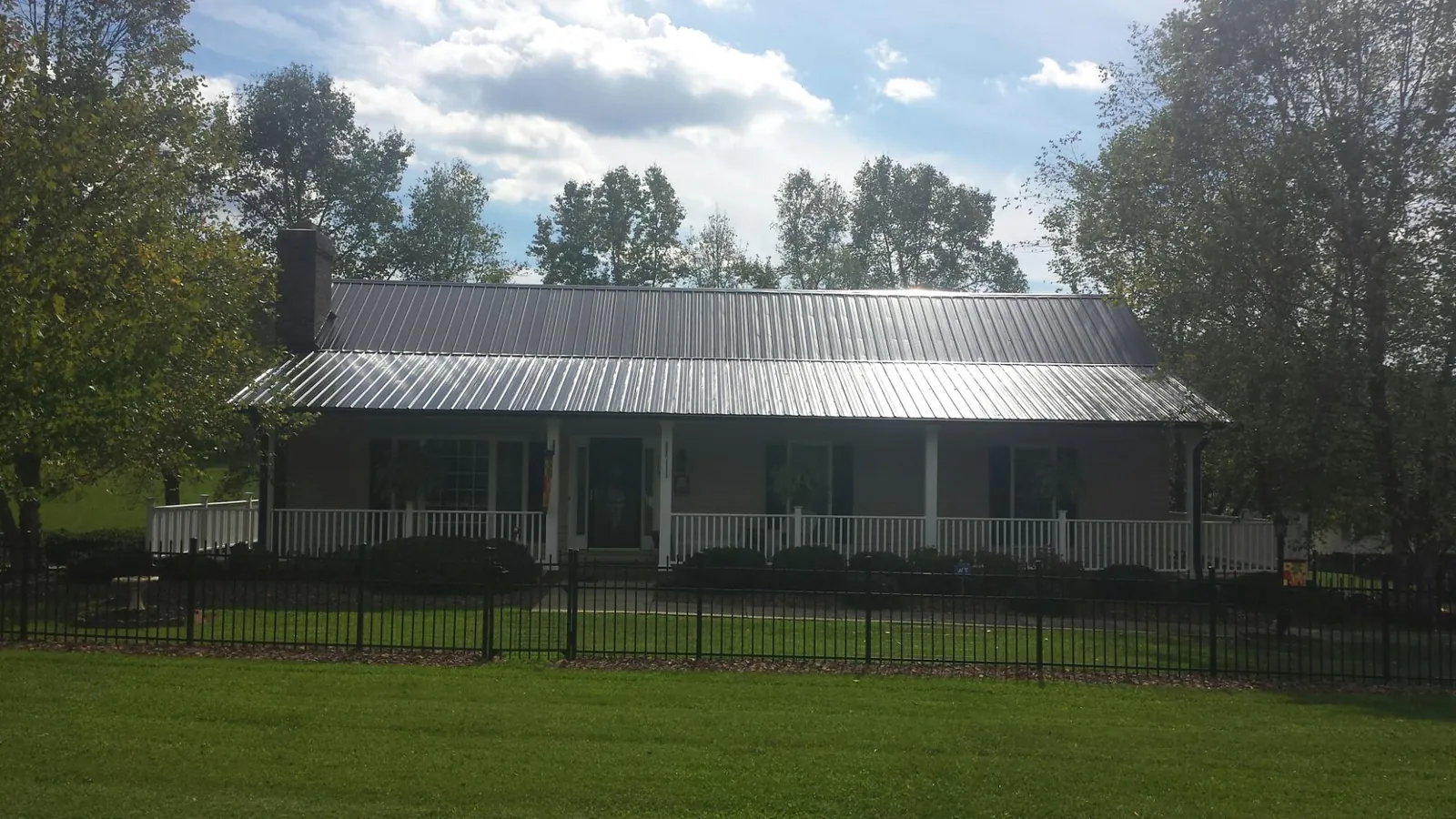 Gray metal roof on a brick ranch with a full width front porch — Gutter Guard Installation work by our crew in Pilot Rock